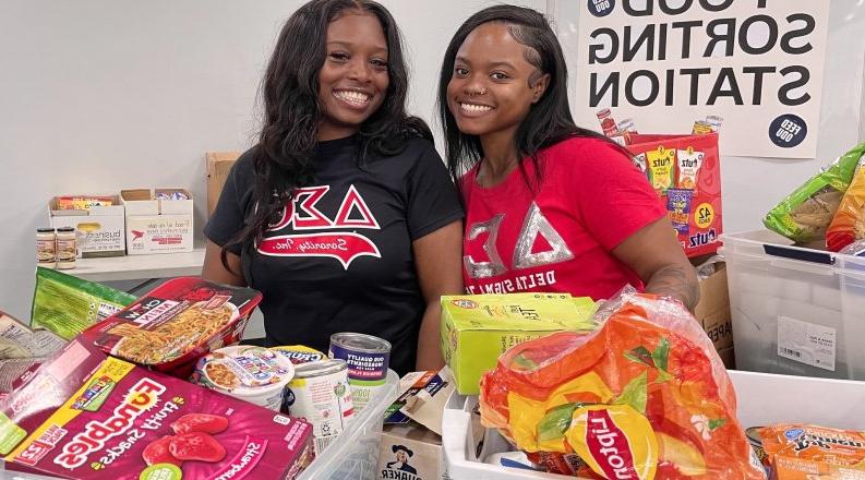 Two female students sort food items for donation.